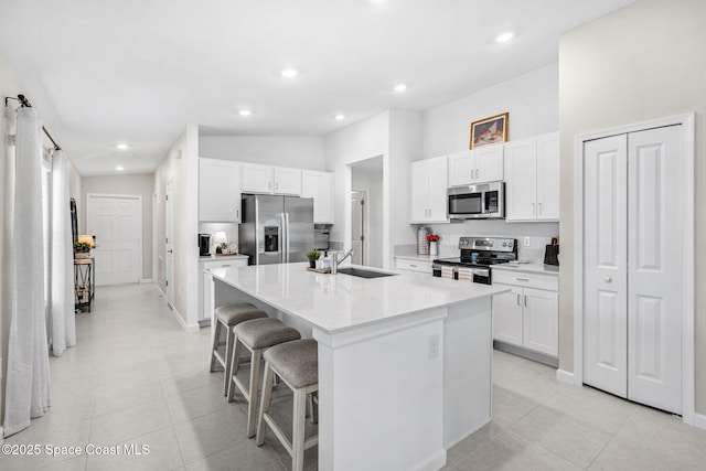 kitchen featuring a kitchen bar, white cabinetry, an island with sink, and stainless steel appliances