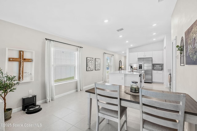 tiled dining space featuring vaulted ceiling