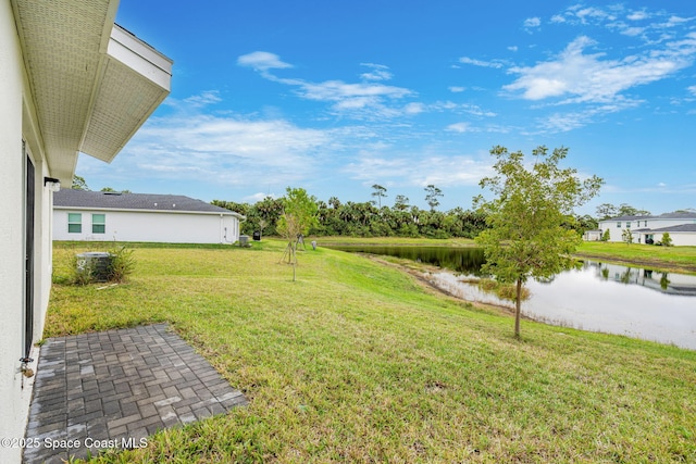 view of yard with a water view and central AC