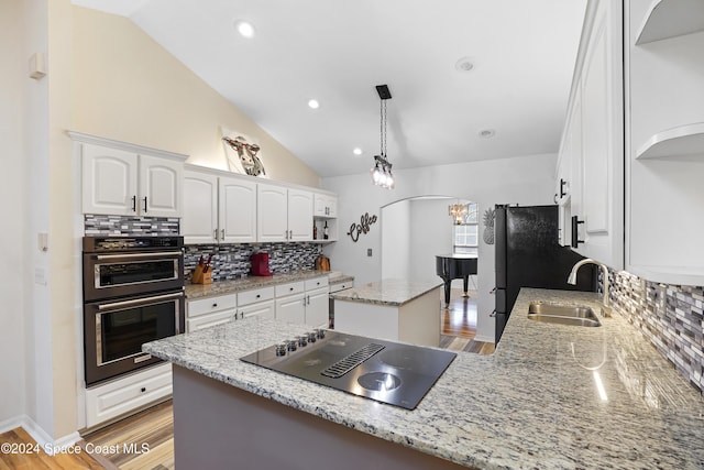 kitchen with light wood-type flooring, black electric cooktop, double oven, sink, and white cabinetry