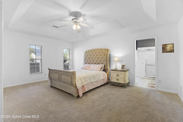 carpeted bedroom featuring a tray ceiling and ceiling fan