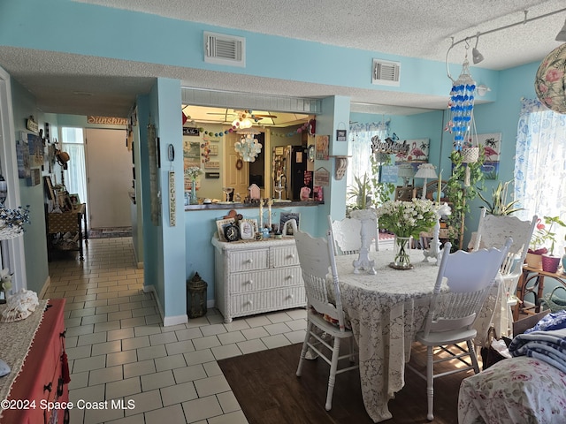 tiled dining area with ceiling fan and a textured ceiling