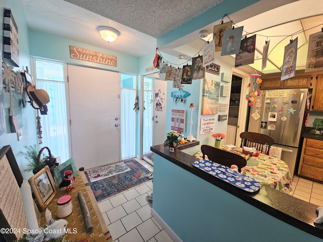 kitchen featuring a textured ceiling, stainless steel refrigerator, and light tile patterned flooring