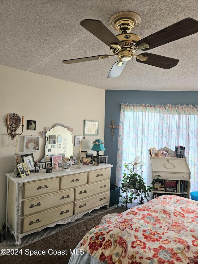 carpeted bedroom featuring ceiling fan and a textured ceiling