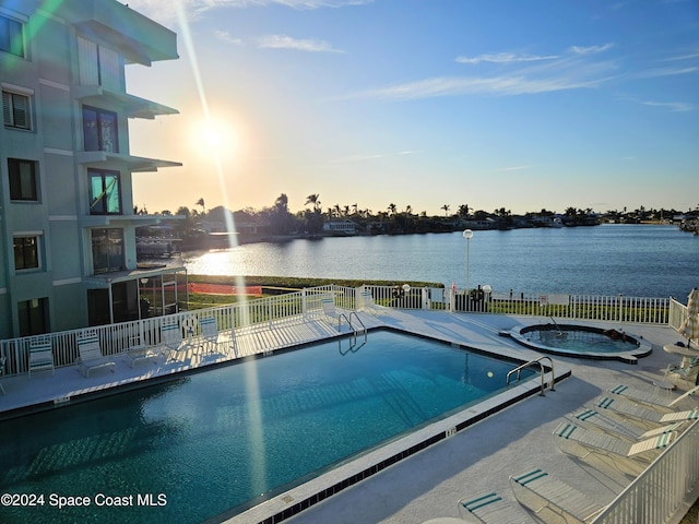 pool at dusk with a patio and a water view