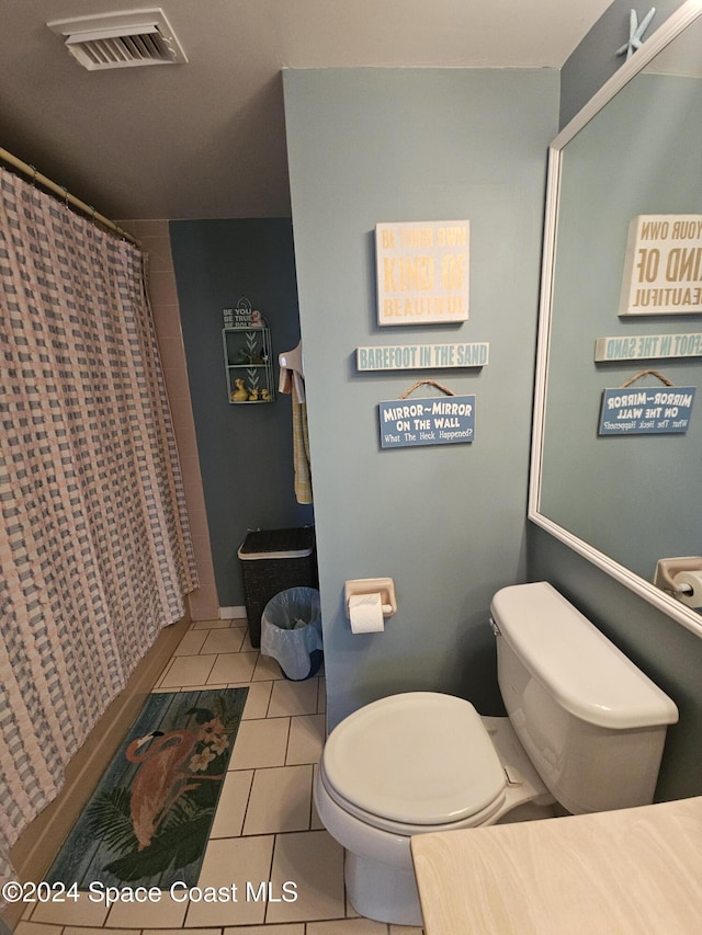 bathroom featuring toilet, a shower with shower curtain, and tile patterned floors