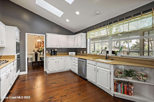 kitchen with appliances with stainless steel finishes, a skylight, white cabinetry, and sink