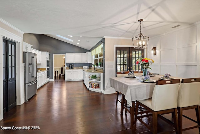 dining room with sink, french doors, dark wood-type flooring, a textured ceiling, and lofted ceiling