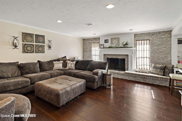 living room featuring a fireplace, dark hardwood / wood-style flooring, ornamental molding, and a textured ceiling