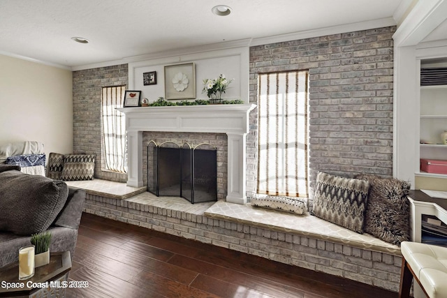 living room with crown molding, a fireplace, brick wall, and hardwood / wood-style flooring