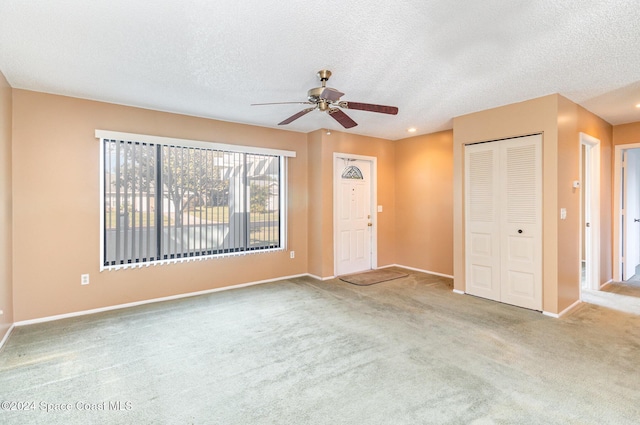 unfurnished living room with light carpet, a textured ceiling, and ceiling fan