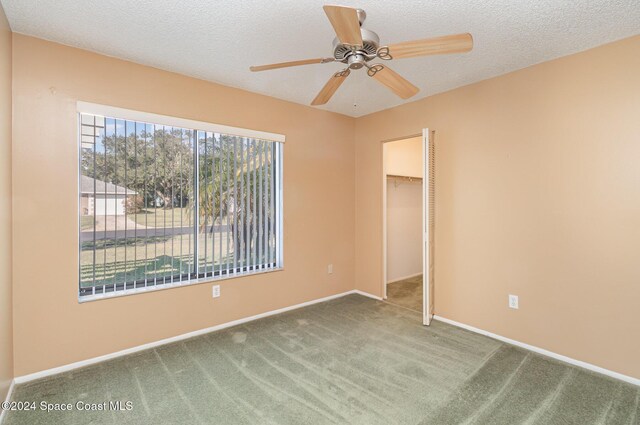 carpeted spare room featuring a textured ceiling and ceiling fan