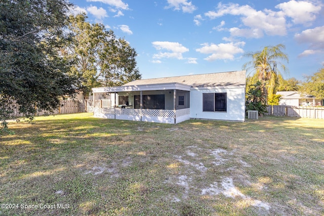 rear view of house with a yard, central AC unit, and a sunroom