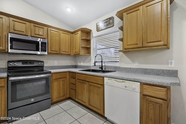 kitchen with sink, light tile patterned floors, stainless steel appliances, and vaulted ceiling