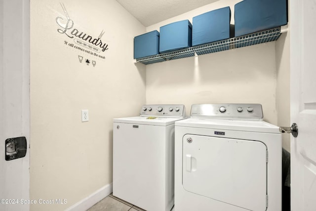 clothes washing area featuring washing machine and clothes dryer, light tile patterned floors, and a textured ceiling