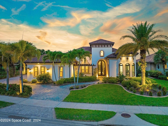 mediterranean / spanish-style home featuring a lawn and french doors