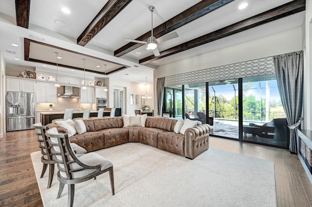 living room featuring beam ceiling, light hardwood / wood-style flooring, ceiling fan, and sink