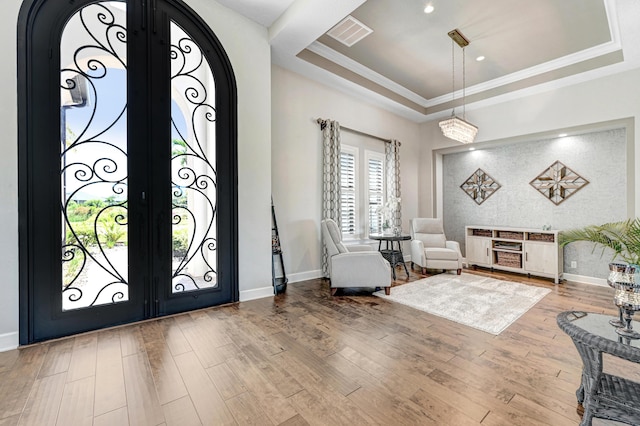 entryway featuring wood-type flooring, a tray ceiling, and ornamental molding