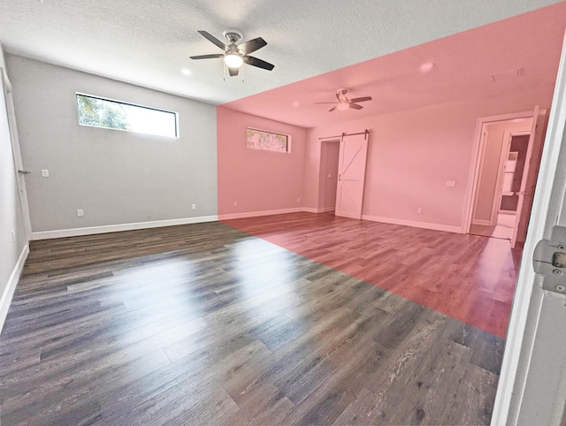 empty room featuring a textured ceiling, a barn door, and dark hardwood / wood-style floors