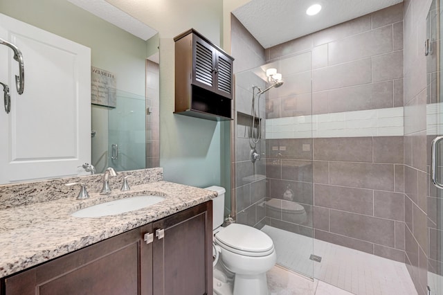 bathroom featuring vanity, a shower with door, tile patterned flooring, toilet, and a textured ceiling