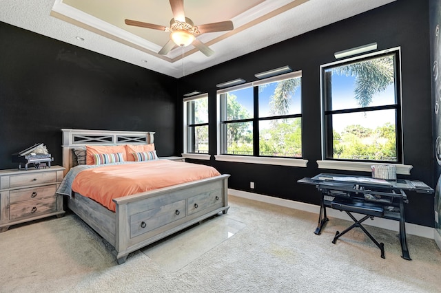 bedroom featuring ceiling fan, light carpet, and a tray ceiling