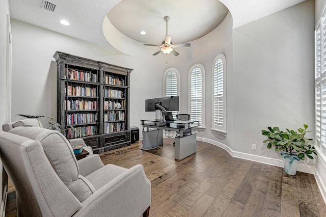 living area featuring hardwood / wood-style floors, ceiling fan, a raised ceiling, and a textured ceiling