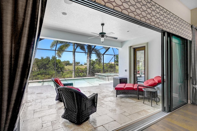 view of patio / terrace featuring glass enclosure, ceiling fan, and a swimming pool with hot tub