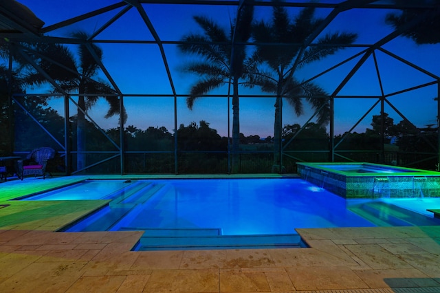 pool at dusk featuring an in ground hot tub, a patio, and glass enclosure