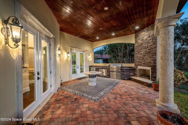 view of patio with an outdoor stone fireplace, area for grilling, sink, and french doors