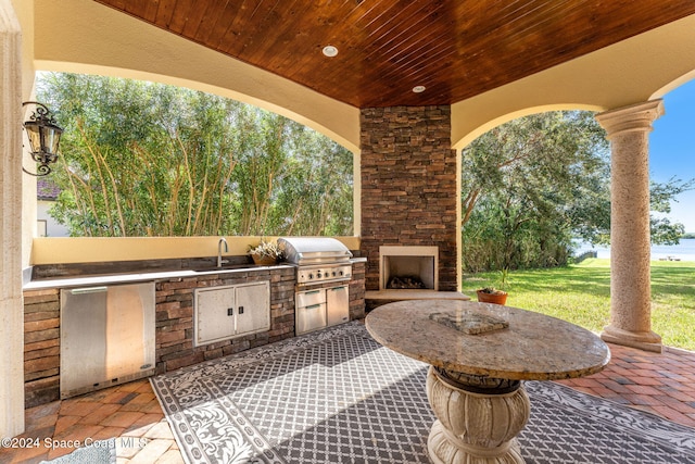 view of patio / terrace with area for grilling, an outdoor stone fireplace, sink, and grilling area