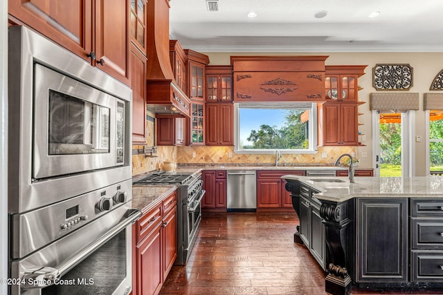 kitchen featuring appliances with stainless steel finishes, light stone counters, crown molding, sink, and dark hardwood / wood-style floors