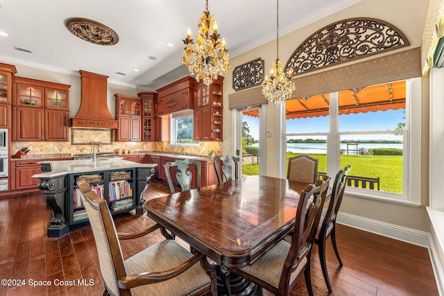 dining room featuring crown molding, dark hardwood / wood-style flooring, a chandelier, and plenty of natural light