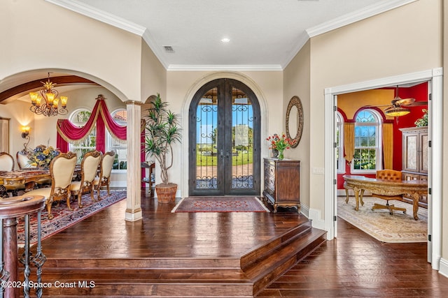 entryway featuring crown molding, french doors, dark wood-type flooring, and an inviting chandelier