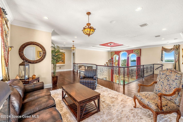 living room with wood-type flooring, a textured ceiling, and crown molding