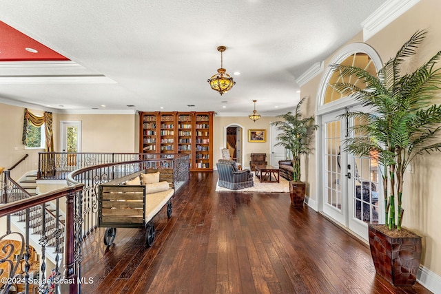 interior space with a textured ceiling, dark hardwood / wood-style floors, and ornamental molding