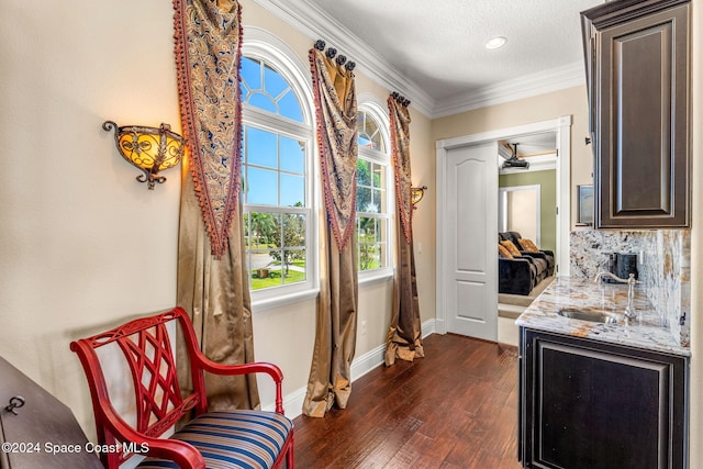 living area with dark hardwood / wood-style flooring, crown molding, sink, and a textured ceiling