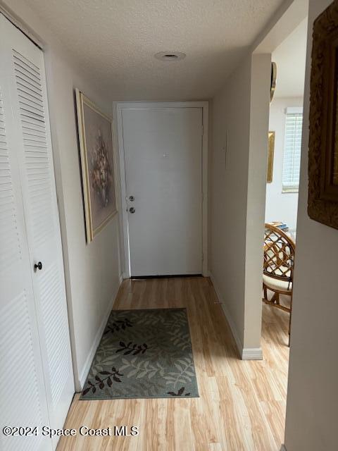 hallway featuring light hardwood / wood-style floors and a textured ceiling