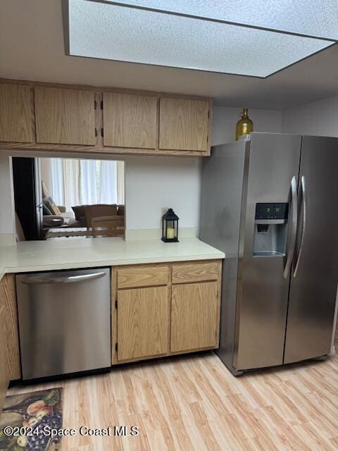 kitchen with appliances with stainless steel finishes and light hardwood / wood-style flooring