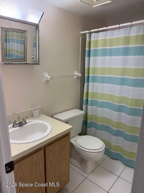 bathroom featuring tile patterned flooring, vanity, toilet, and walk in shower