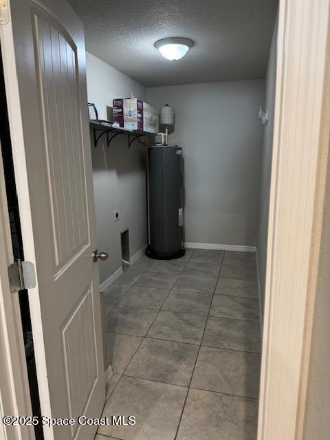 laundry room with electric water heater, tile patterned floors, hookup for an electric dryer, and a textured ceiling