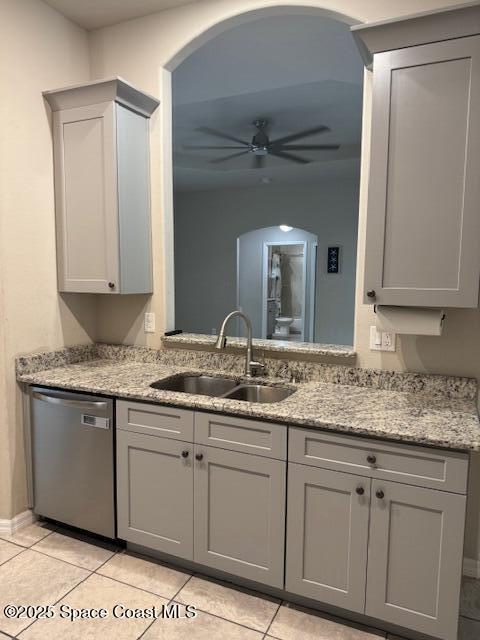 kitchen featuring light stone countertops, stainless steel dishwasher, gray cabinets, light tile patterned floors, and sink