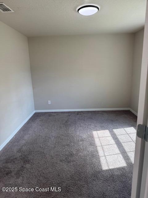 unfurnished room with dark colored carpet and a textured ceiling