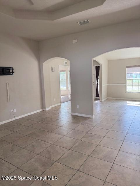 unfurnished room featuring light tile patterned floors and a tray ceiling