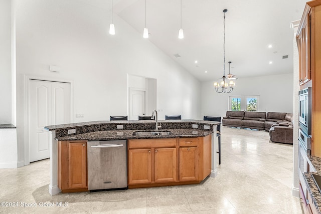 kitchen with sink, high vaulted ceiling, pendant lighting, dark stone counters, and a kitchen island with sink