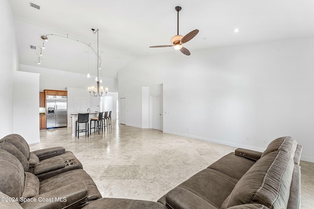 living room featuring high vaulted ceiling and ceiling fan with notable chandelier