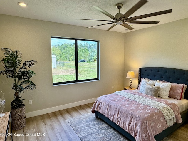 bedroom featuring hardwood / wood-style flooring, ceiling fan, and a textured ceiling