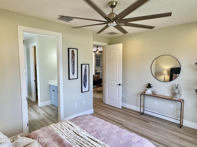 bedroom with connected bathroom, light hardwood / wood-style floors, and ceiling fan