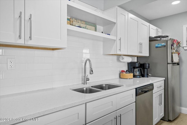 kitchen featuring dishwasher, white cabinets, light stone counters, and sink