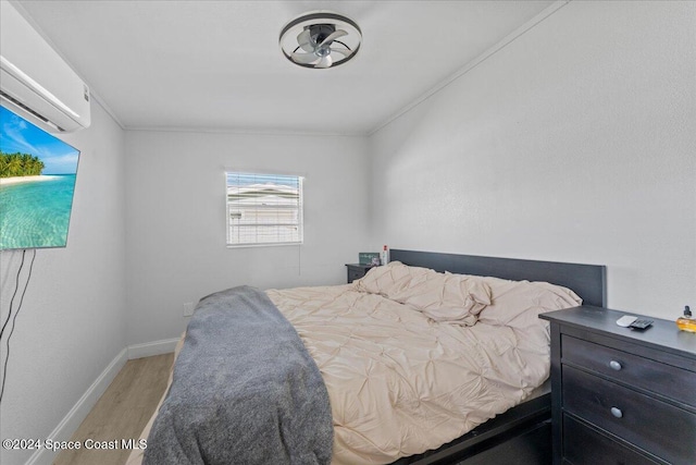 bedroom featuring a wall mounted air conditioner, wood-type flooring, and ornamental molding