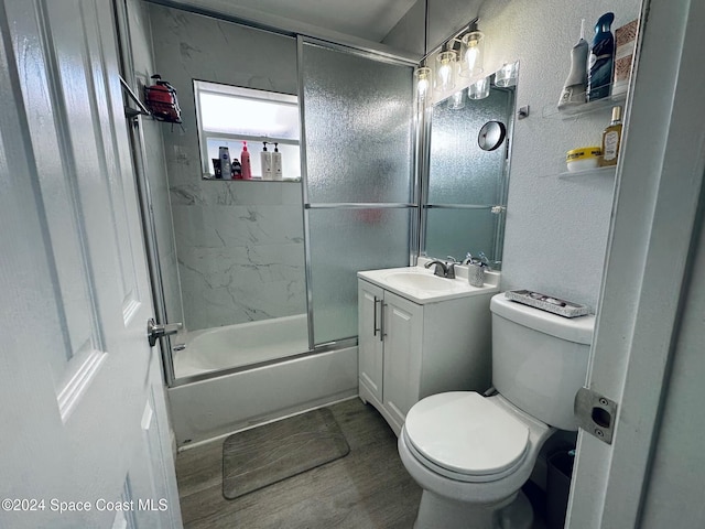 full bathroom with wood-type flooring, vanity, toilet, and bath / shower combo with glass door